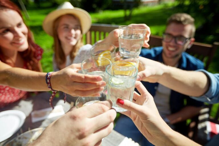 Frauen und Männer stossen zum Trinken bei Hitze an